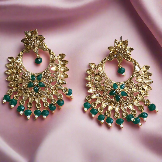 Pair of gold and green earrings on a gray background