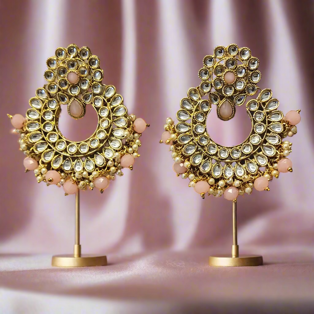 Pair of gold and pink earrings on a gray surface