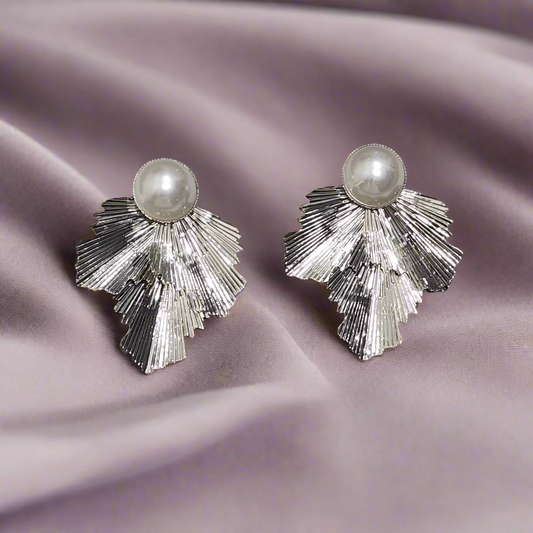 Pair of silver earrings with pearl centers on a gray surface