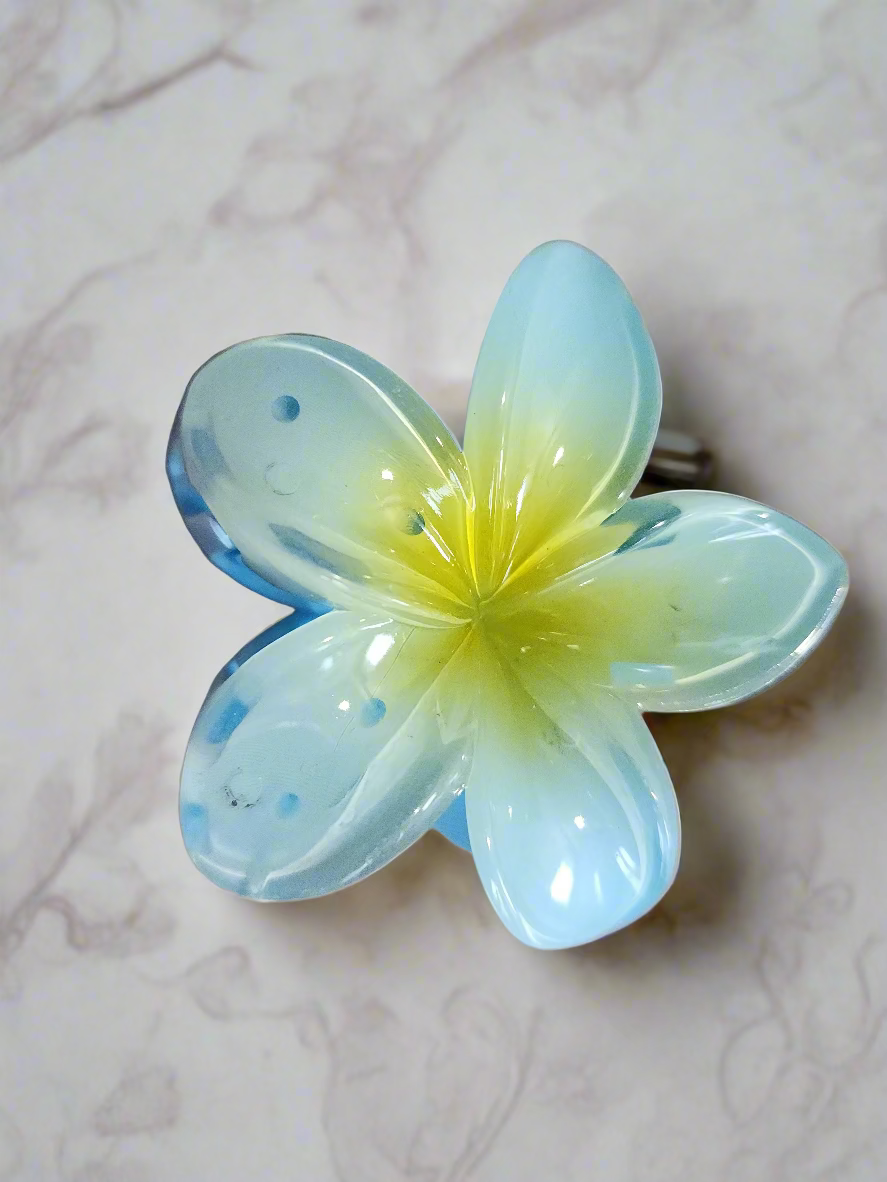 Flower-shaped clip with blue and yellow gradient on a beige background