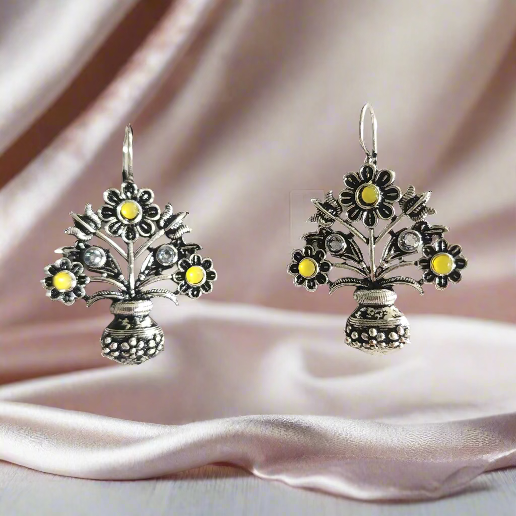 Pair of silver earrings with floral designs and yellow stones on a gray background