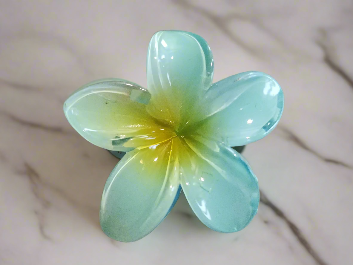Artificial flower with light blue petals and yellow center on a marble background