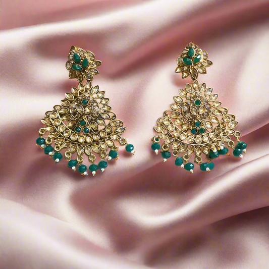 Pair of gold and green earrings on a light gray background