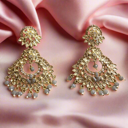 Pair of gold earrings with intricate designs on a gray surface