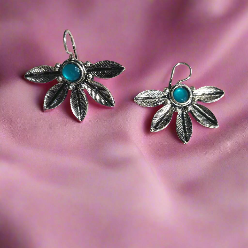 Silver leaf-shaped earrings with turquoise stones on a light gray background