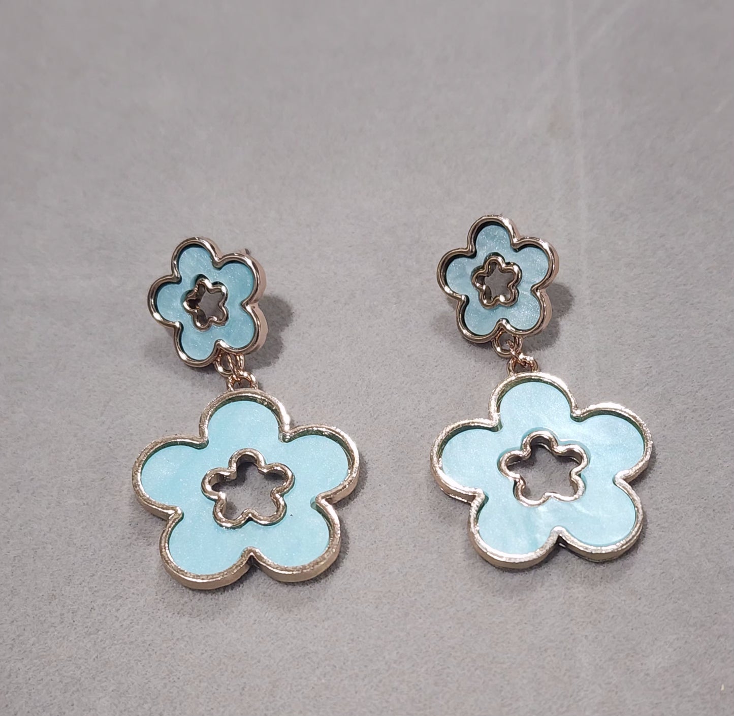 Flower-shaped earrings on a soft Blue background