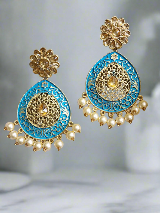 Ornate earrings with blue and gold design on a gray background