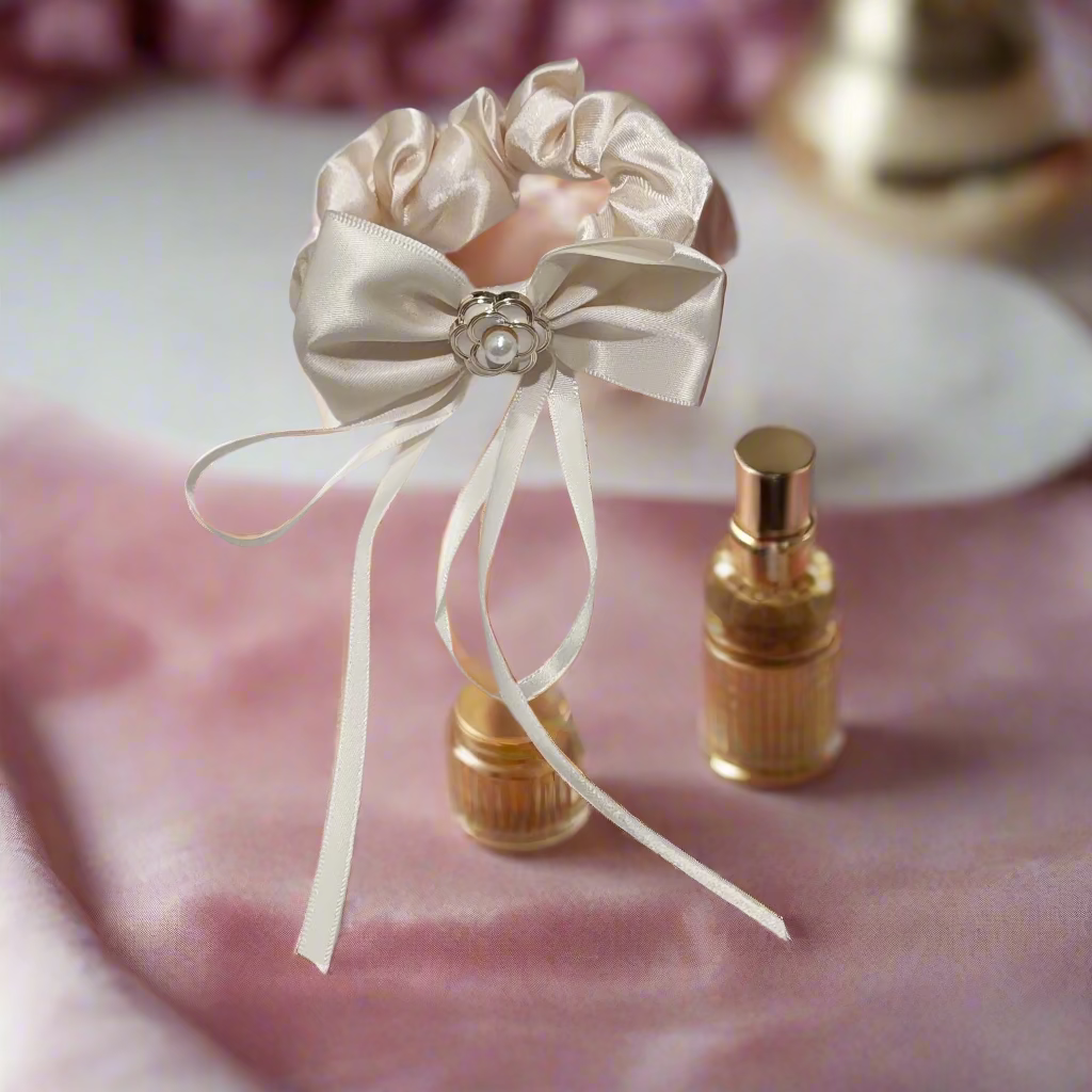 Silk scrunchie with bow and pearl embellishment on a light gray background