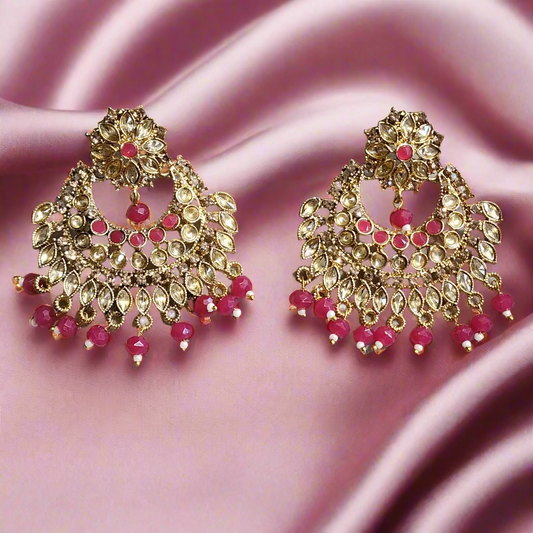 Pair of gold and pink earrings on a gray background