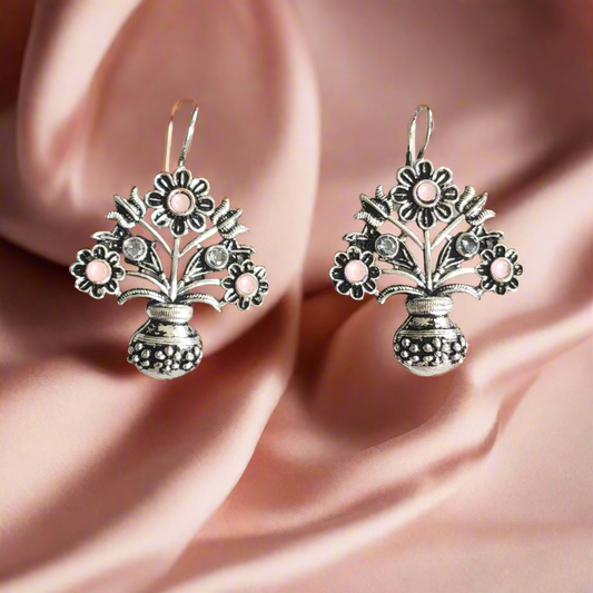 Pair of silver earrings with pink stones on a gray background