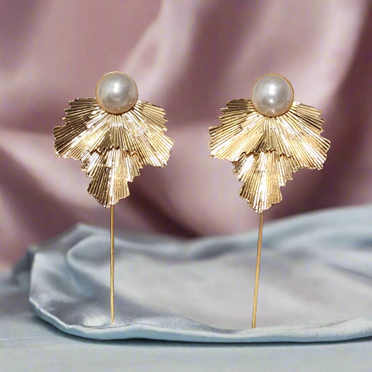 Pair of gold earrings with pearl centers on a gray background
