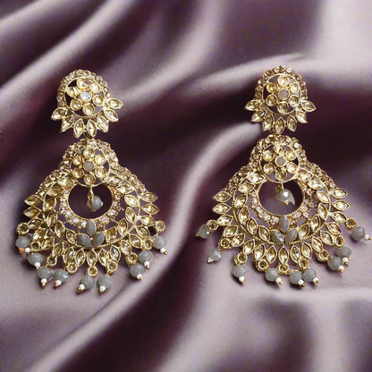 Gold and gray earrings on a gray surface
