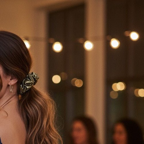 Woman in a blue dress standing in a party setting with blurred people and lights in the background