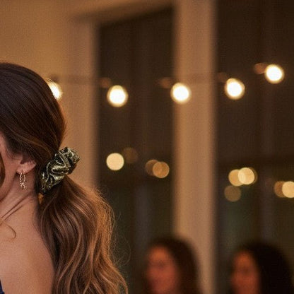 Woman in a blue dress standing in a party setting with blurred people and lights in the background